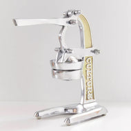 Silver and brass manual citrus juicer with lever handles and collection cup on wide base.