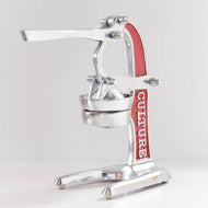 Manual citrus juicer with red and silver metal construction, lever arm, and cone reamer in collection bowl.