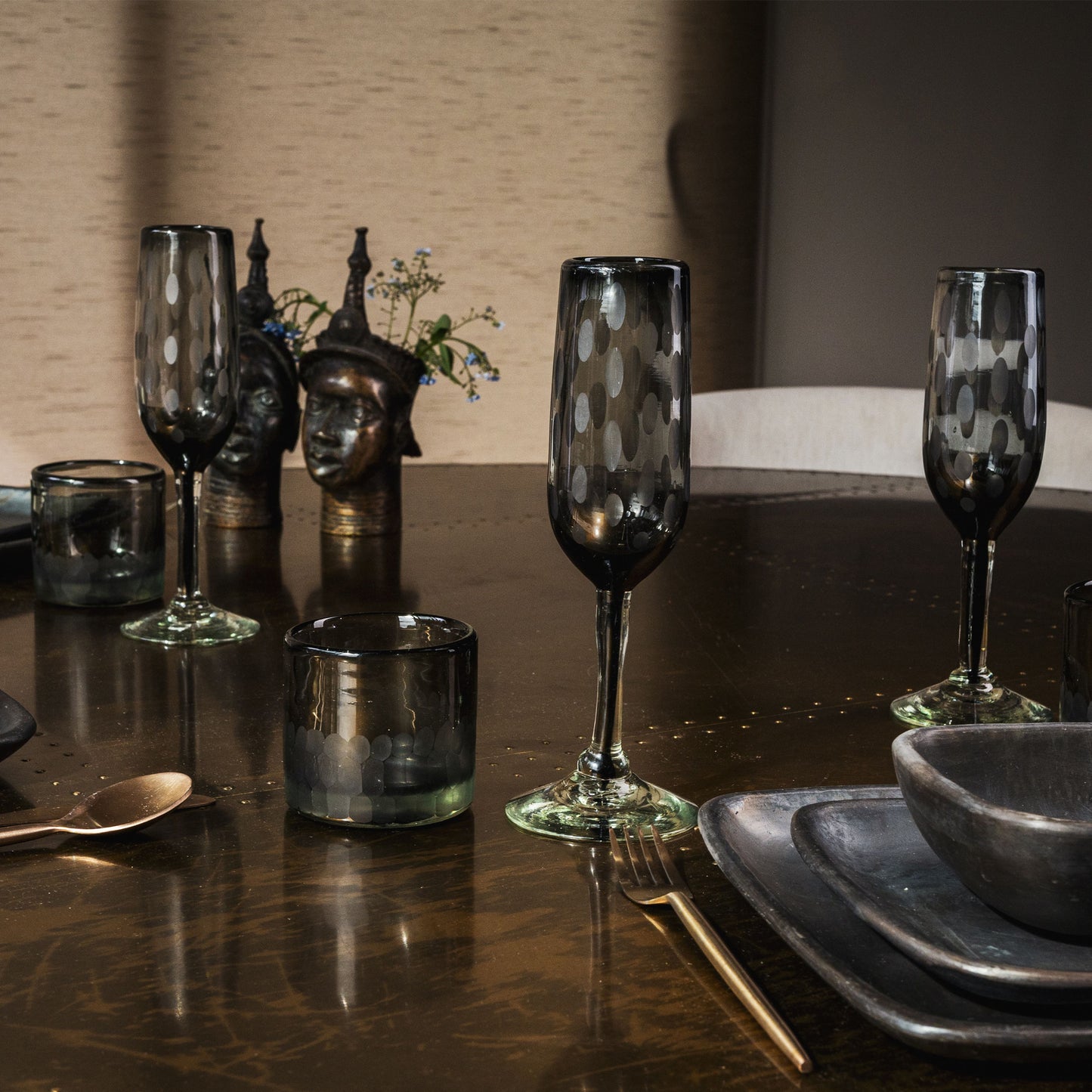 Two clear champagne flutes with white etched dot pattern on dark table setting.