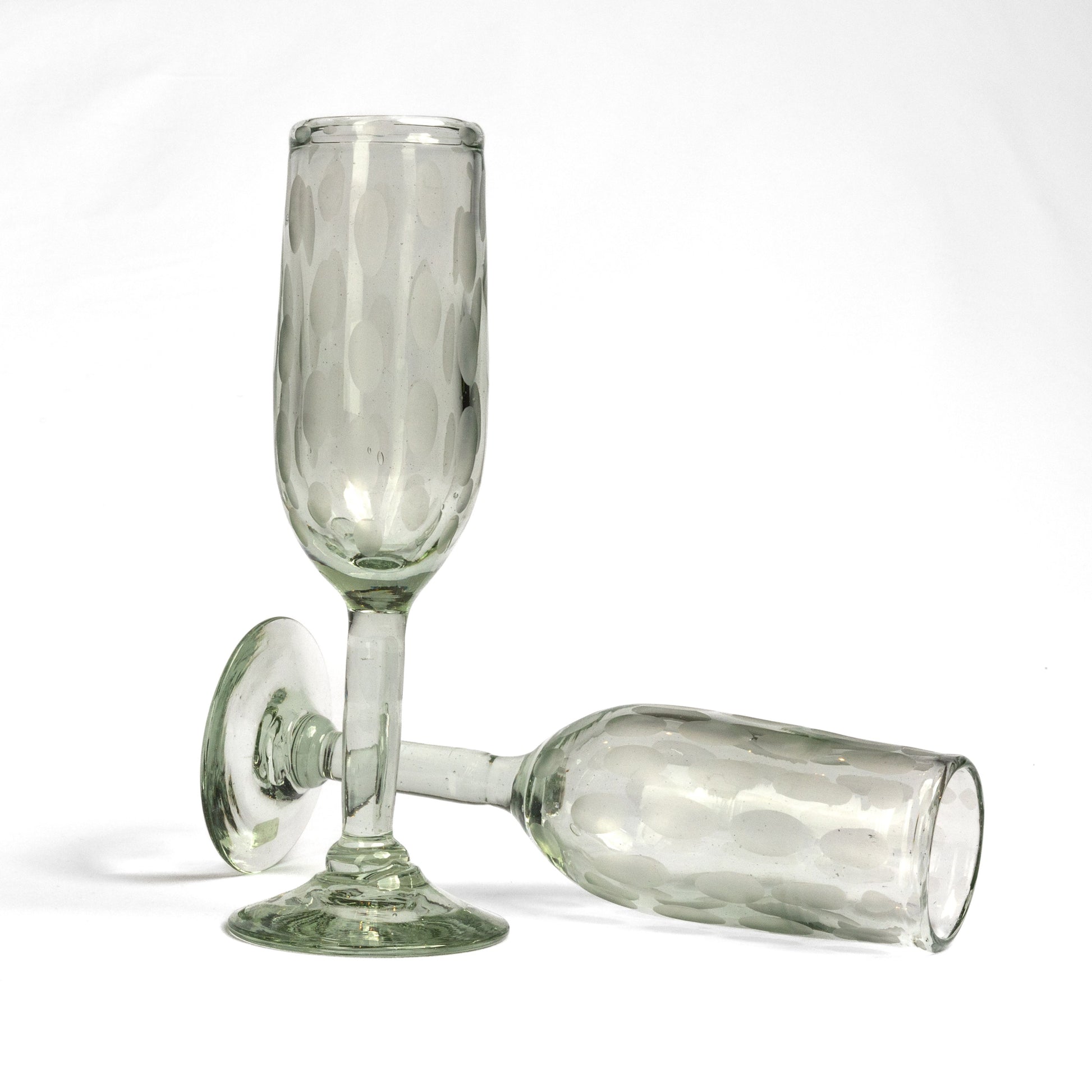 Two clear glass champagne flutes with etched surface patterns and rounded bases on white background.