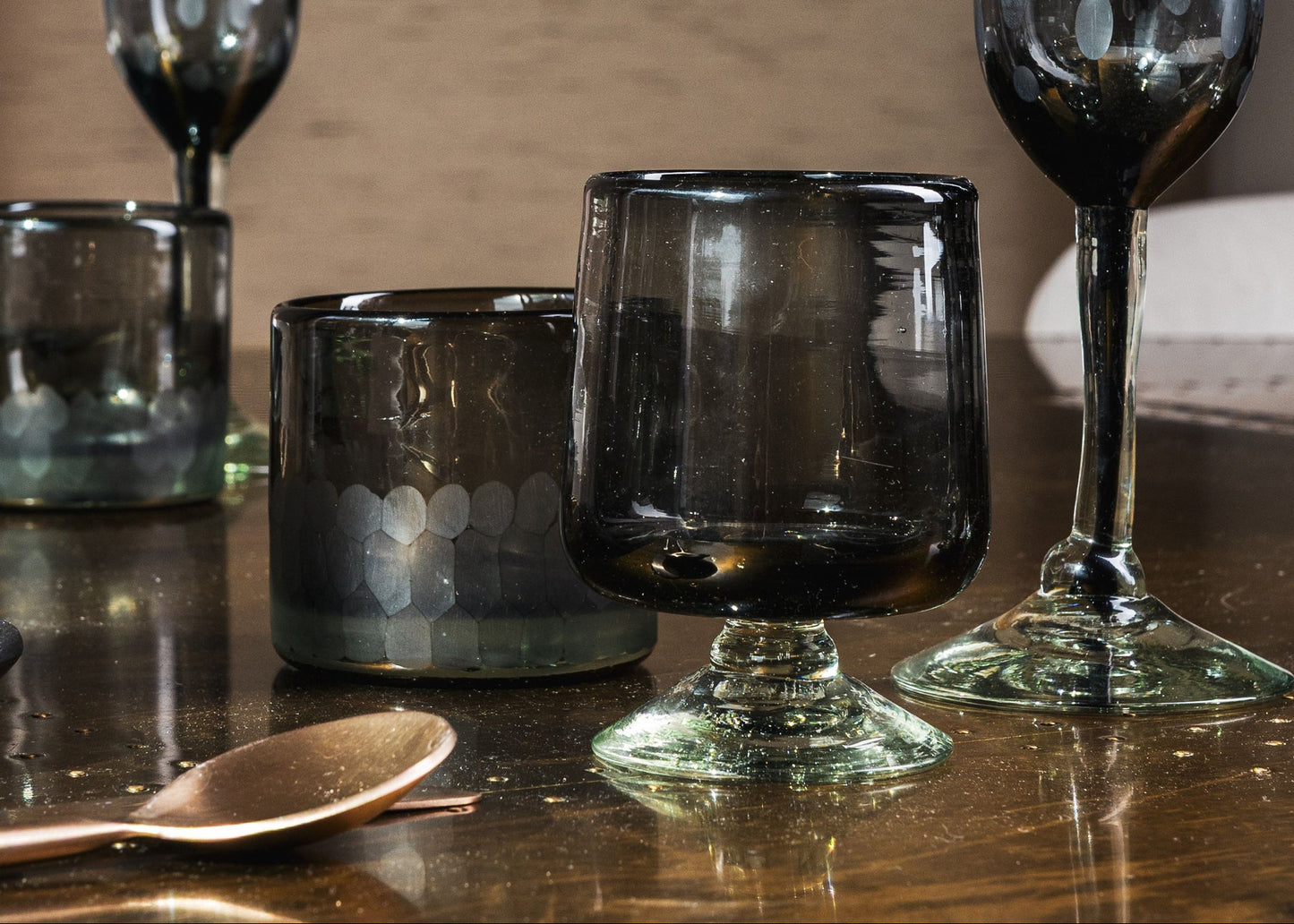 Set of black glass tumblers with white etching on a reflective surface.