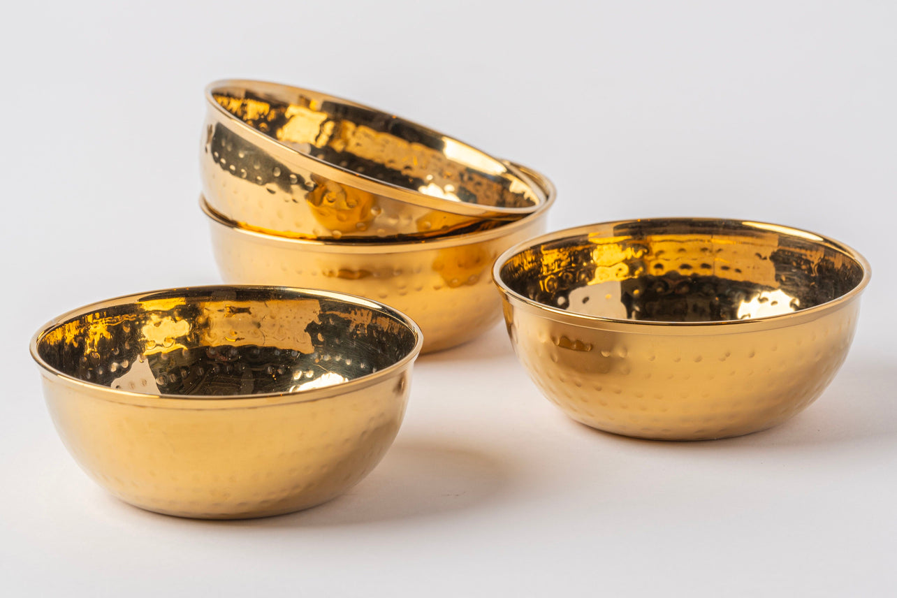 Four gold-toned stainless steel bowls with hammered texture surface and wide rims.